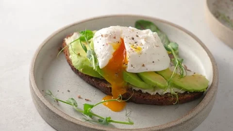 Avocado toast with poached egg. Sprinkle pepper on poached egg over bread toast Video stock 171721746