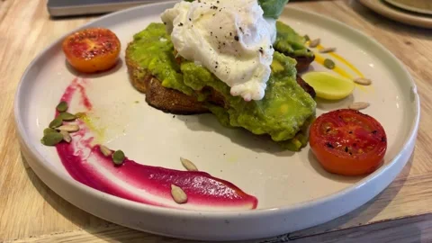 Avocado Toast with Poached Eggs on Plate Cafe Breakfast Dish Stock Footage 333828242