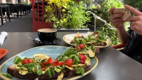 Avocado toasts being shot with smartphone in male hands in street cafe Stock Footage 246355959