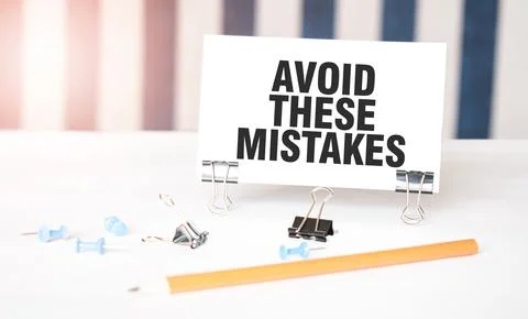AVOID THESE MISTAKES sign on paper on white desk with office tools. Blue an.. Foto stock