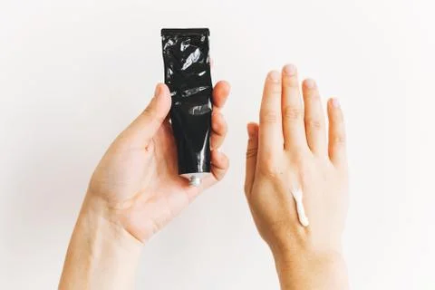 Avoiding dry skin. Hands holding cream in black tube for moisturizing skin af Stock Photos