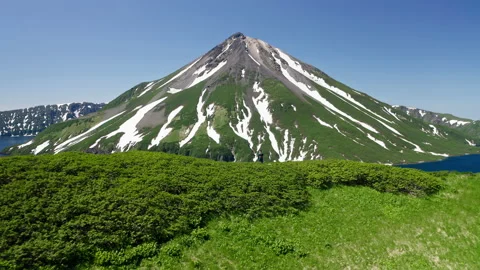 Awesome aerial view. Man on greenery hill. Snowy volcano, blue water lagoon Stock Footage 169211237