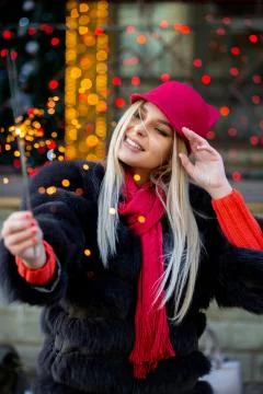 Awesome blonde model having fun with sparklers against garlands blurred backg Stock Photos