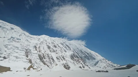 Awesome round cloud hover in sunny blue sky above snowy mountain peak, panorama Stock Footage 127081345