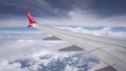 Awesome view of a wing and white clouds in blue sky from plane porthole Видео 348545940