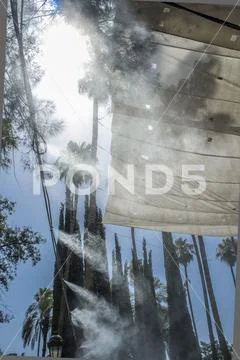 Awning and sprinklers splashing vaporized water at public park Stock Photos