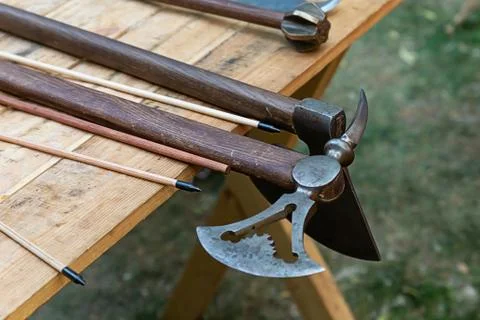 Ax combat openwork blade, arrow bow on the background of maces on the table Stock Photos