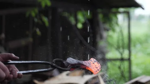 An ax heated by a blacksmith is kept on the fire under raindrops. Stock Footage 141766792