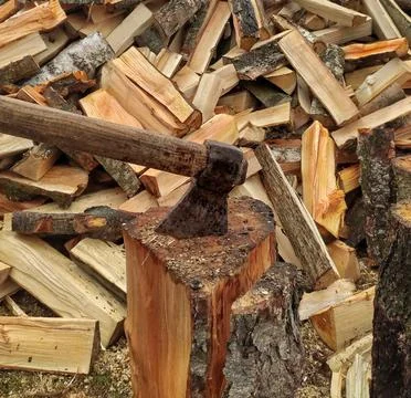 An ax in a log on a background of firewood Stock Photos