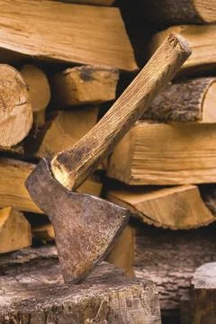 The ax is stuck in a log against the backdrop of chopped firewood lying in a Stock Photos
