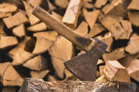 The ax is stuck in a log against the backdrop of chopped firewood lying in a Stock Photos