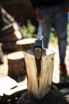 Axe blade wedged into a split log with a woodcutter behind Stock Photos