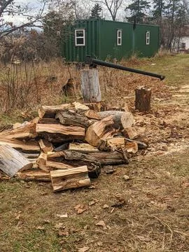 An axe in a log beside a pile of split wood Stock Photos