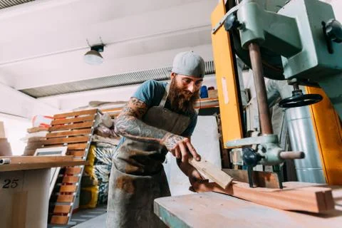 Axe maker cutting wood for axe handle in workshop Photos