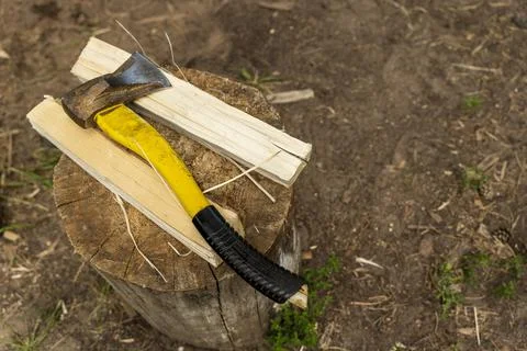 An axe with a plastic handle and a split wooden log on a stump Stock Photos