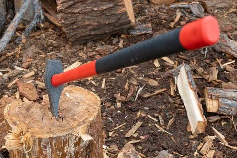 An axe with a plastic, rubber handle, which is stuck in a chock, a log Stock Photos