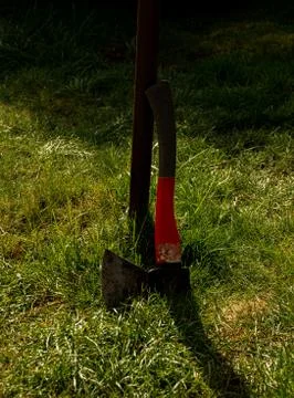 Axe put down a pillar in the garden with green grass Stock Photos