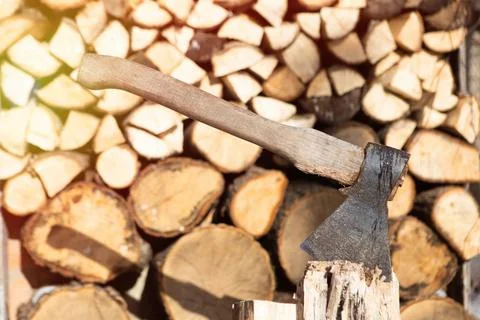Axe set in chopping block in front of a woodpile background Stock Photos