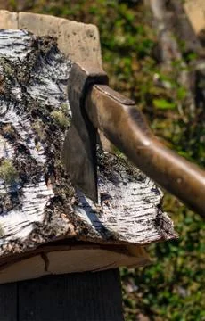 Axe stuck in birch bark on a birch log in the yard on the street Stock-Fotos