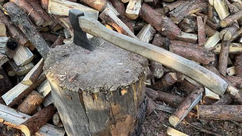 Axe Stuck in Chopping Block with Pile of Firewood Stock Photos