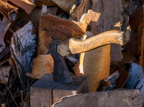 The axe stuck in a log in the yard about a woodpile on the street Stock Photos