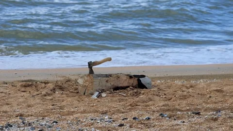 An axe is stuck in a tree stump against the background of a raging sea. Family Stock-Footage 303935386