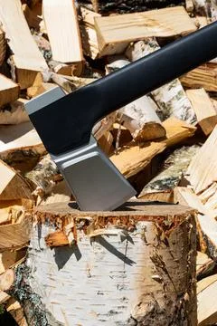 An axe stuck in a wooden stump against a background of punctured logs. Stock Photos