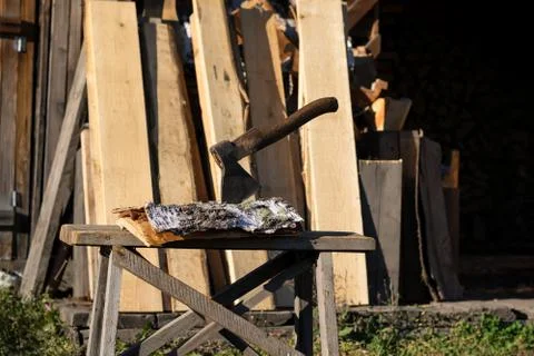 Axe thrust in a birch bark on a log near the woodpile. Stock Photos
