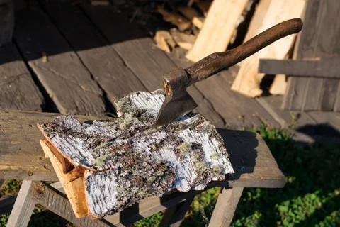 Axe thrust in a birch bark on a log near the woodpile. Stock Photos