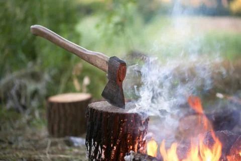 Axe in tree stump and campfire Stock Photos