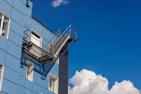 Azure building with a side fire escape, under a sky with fluffy clouds Photos