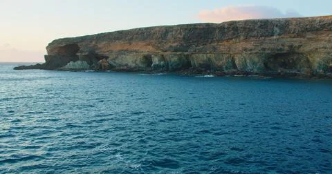 Azure calm ocean waves and rocky black volcanic caves cliffs of Ajuy in Stock Photos