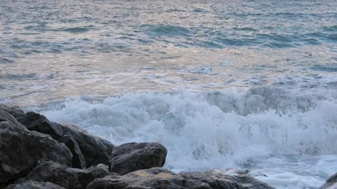 Azure ocean waves run and splash on coast with large rocks in summer evening Stock Footage 257345550
