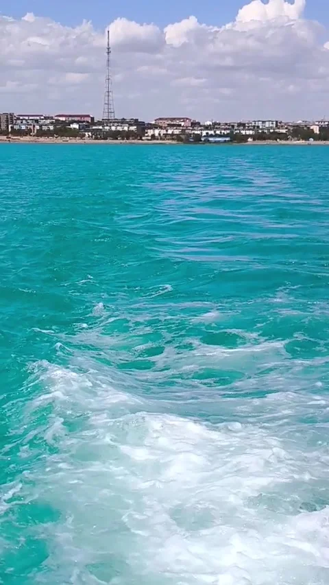 An azure ships wake on the waves, a panorama of the city on the horizon under a Stock Footage 317960086