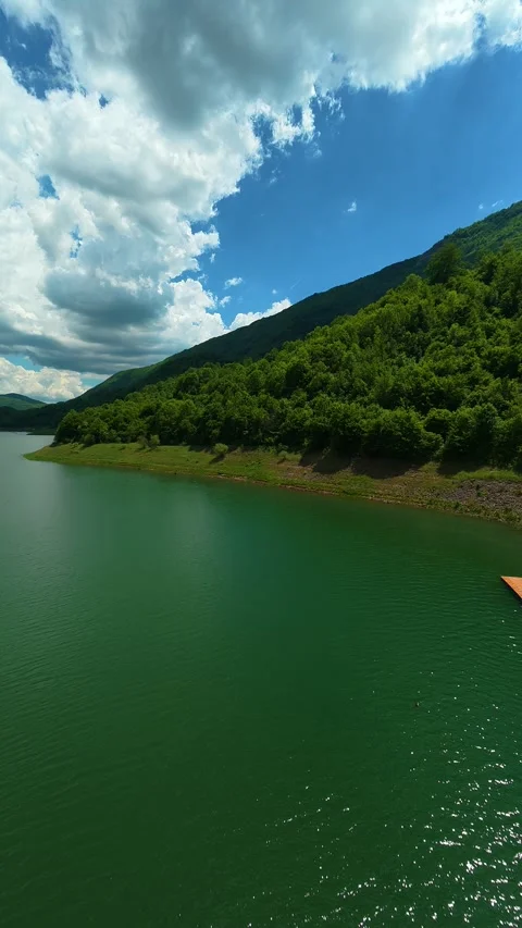 Azure sky above emerald waters, calm and serene. Zavoj Lake, Serbia. Vertical Vídeo Stock 337495489