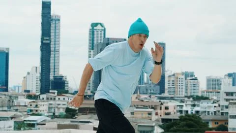 B-boy dancer practicing street dancing at rooftop with city view. Hiphop. Stock Photos
