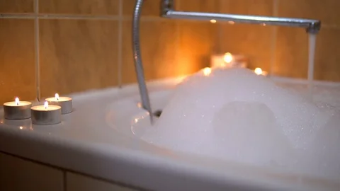 Babble bath with candles, hot water pours in bath, foam, romantic atmosphere Vídeos de archivo 129059085