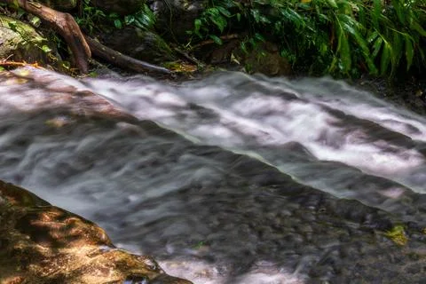 The babbling brook flows over the rocks Stock Photos