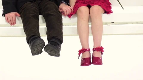 Babies ride on a swing to hold hands, tell each other secrets in the ear. White Stock Footage 75798887