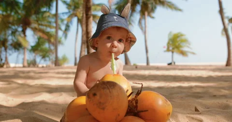 Baby 7 months old on the beach drinking coconut Stock Footage 107331553