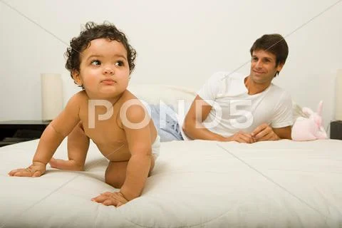 Baby and father on bed Stock Photos