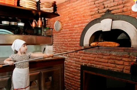 Baby baker getting out a bread from stove Stock Photos