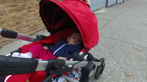 A baby being pushed in a stroller down a city sidewalk Stock Footage 61626891