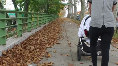 A baby being pushed in a stroller down a city sidewalk Stock Footage 61627114