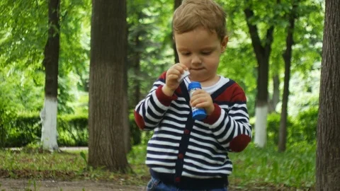 Baby blowing soap bubble outdoors Stock Footage