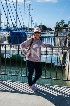 Baby boomer caucasian woman in pink sweatshirt and baseball cap leaning on ir Stock Photos
