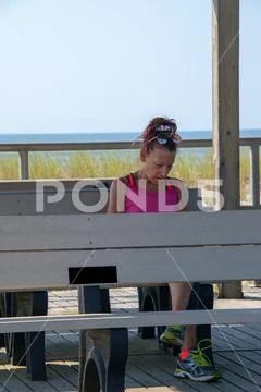 Baby Boomer mature Caucasian woman Sitting on a gray bench looking down with Stock Photos