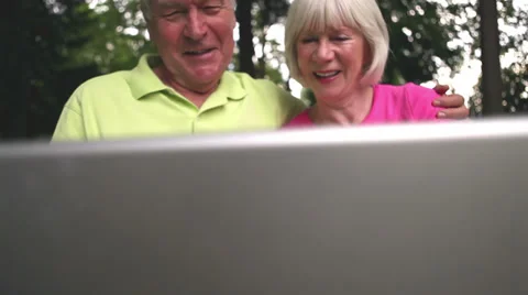 Baby boomer portrait of smiling couple sitting on a park bench. Medium shot. Stock Footage