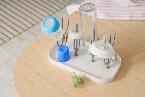 Baby bottle drying rack with clean bottles and pacifier on wooden table, infa Stock Photos