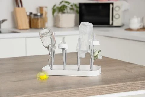 Baby bottle drying rack with clean bottles and pacifier on kitchen countertop Stock Photos